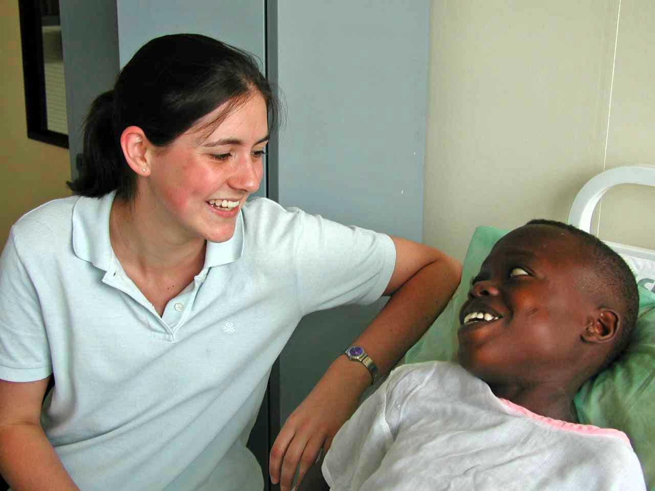 An intern from Projects Abroad sat by a young boys bedside making him laugh during her physiotherapy internship in Ghana. Projects Abroad female intern sat by the bedside of a young boy making him laugh during her physiotherapy internship in Ghana.